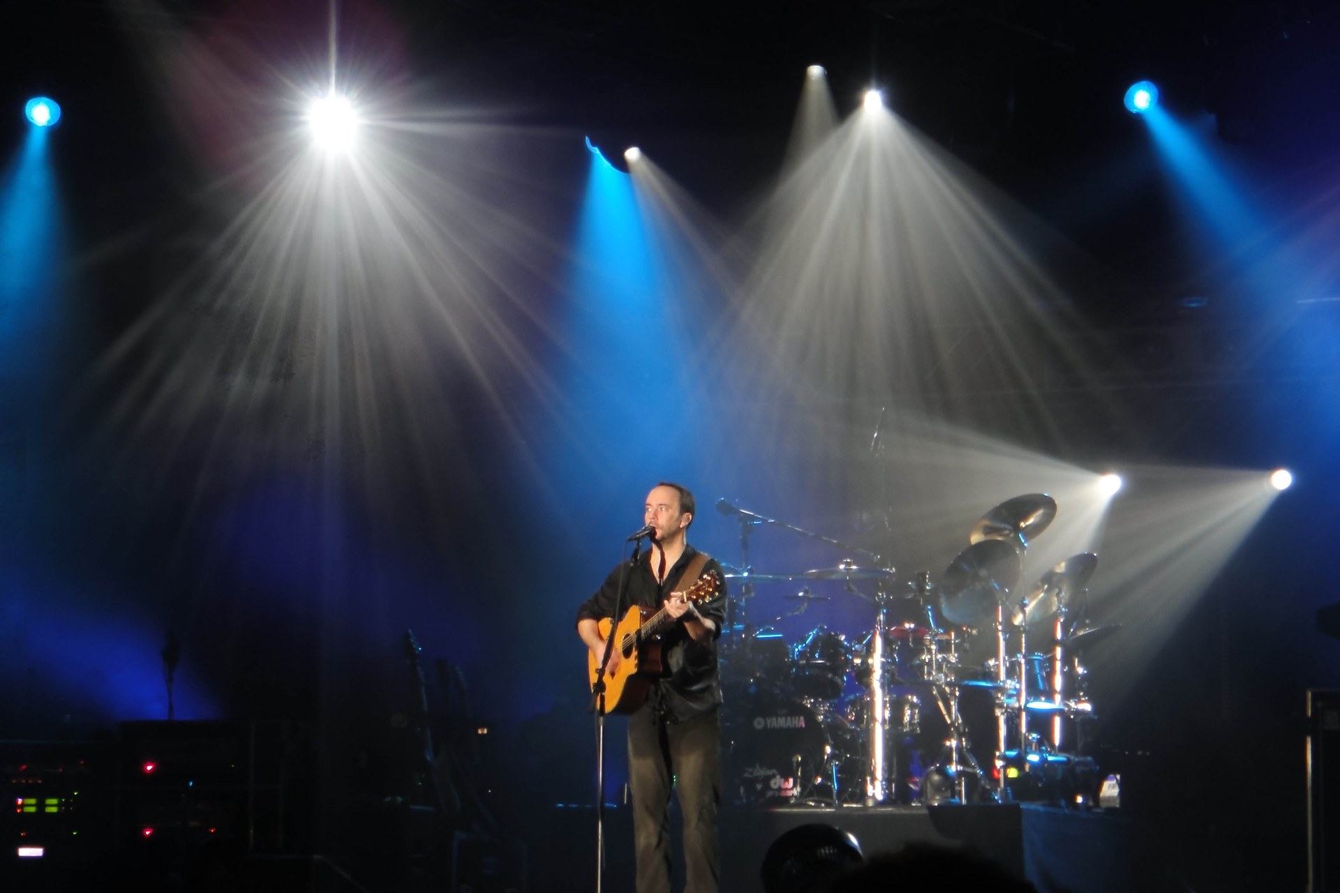 Dave Matthews performing on stage with Dave Matthews Band at Bonnaroo 2010 under blue concert spotlights